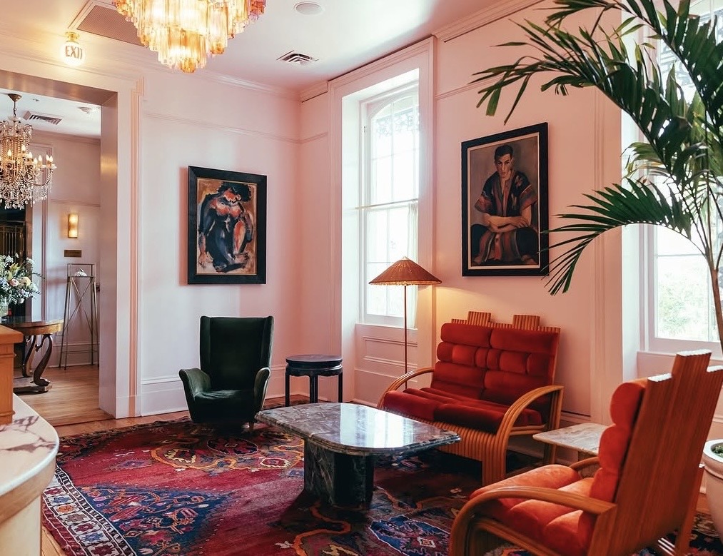 Blush-pink lobby with chandeliers, rattan seating and antique rugs