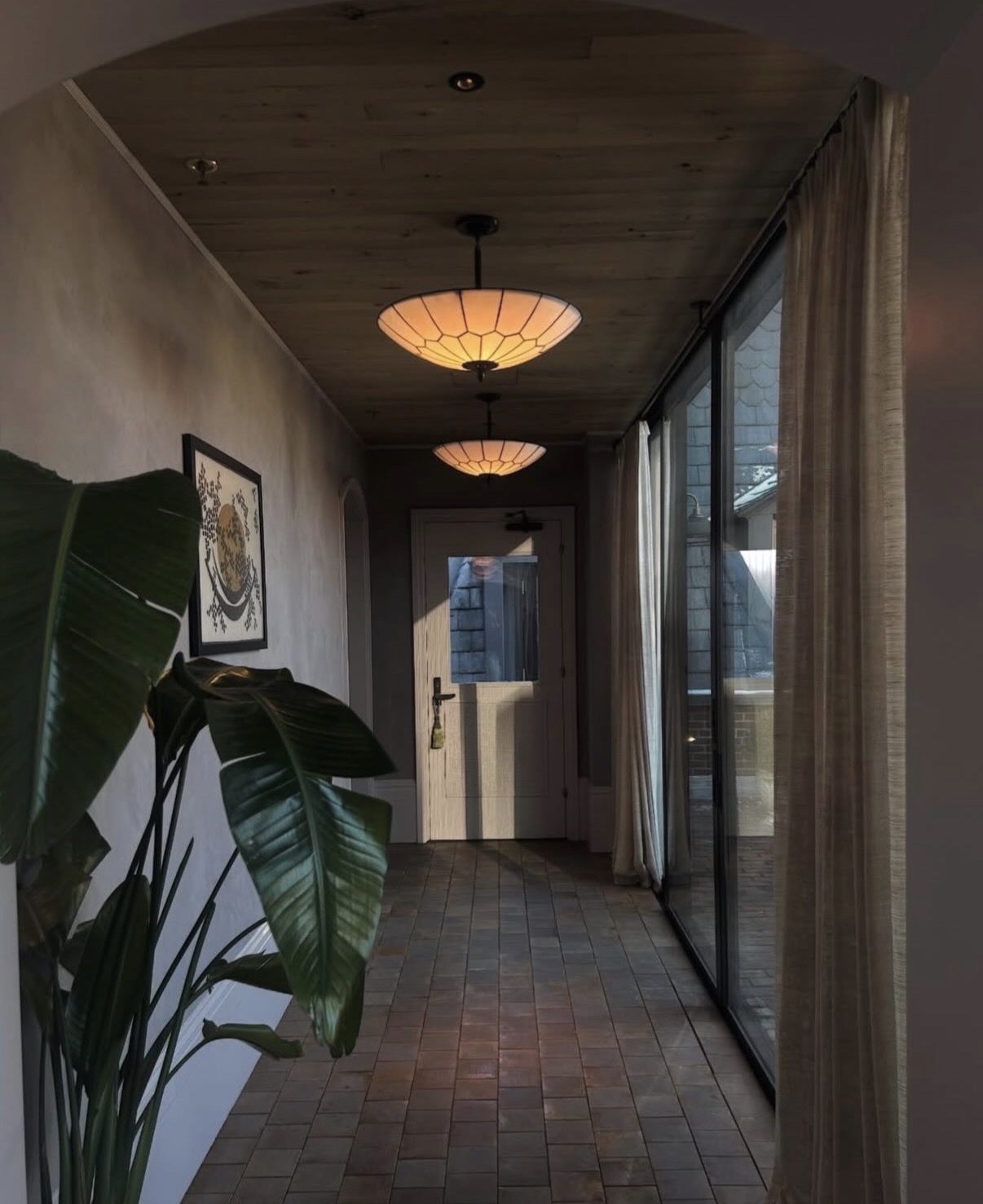 Lantern-lit corridor with terracotta floor and banana palm