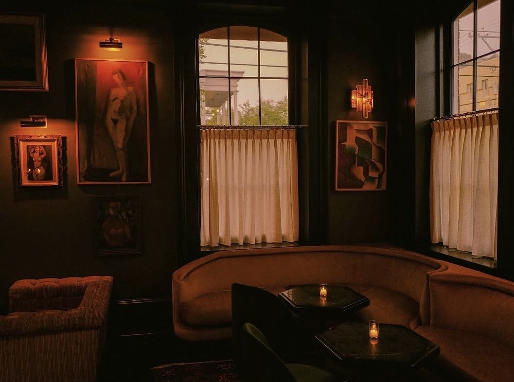 Candlelit bar with velvet banquettes and vintage paintings