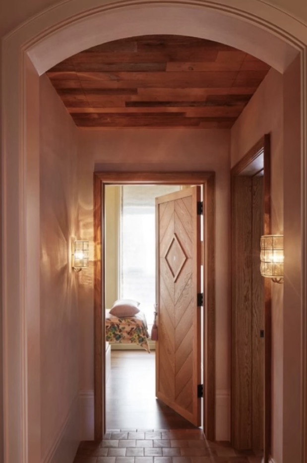 Arched plaster hallway with cedar ceiling and glass sconces